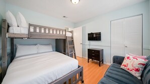 A bedroom with a bunk bed, a desk, a television, and a wardrobe.