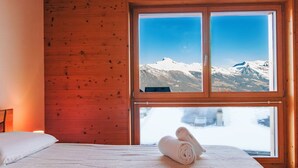 A room with a wooden wall and a large window offering a mountain view. - Moulin du Raé A2 by Interhome (Nendaz)