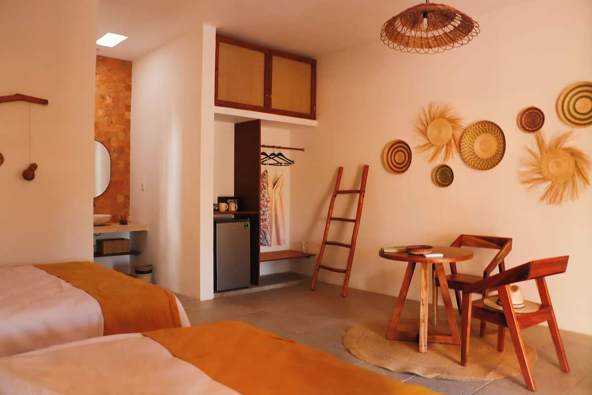 Une chambre avec deux lits, un bureau, une chaise, une échelle et une petite kitchenette.