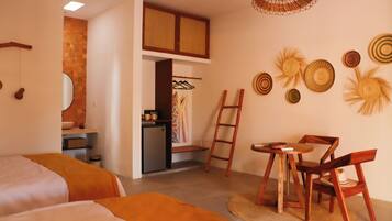 A room with two beds, a desk, a chair, a ladder, and a small kitchenette.