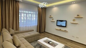 A modern living room with a sectional sofa, a flat-screen TV, and a coffee table. - Delta Sharm Resort - Sharm El-Sheikh (Sharm El Sheikh)