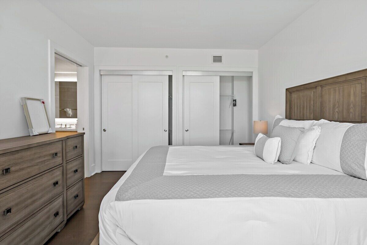 A bedroom with a large bed, a dresser, and a wardrobe.