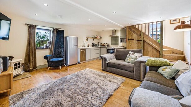 A spacious living area with a sofa, a rug, and a kitchen in the background. - Meagill Cottage, Sleeps 4 With Hot Tub & Parking (Otley)