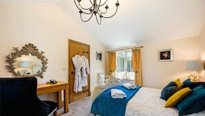 A bedroom with a bed, a chair, a desk, a mirror, and a chandelier. - Meagill Cottage, Sleeps 4 With Hot Tub & Parking (Otley)