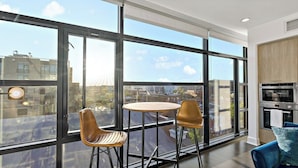 A modern kitchen with a large window, a round table, and two chairs.