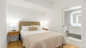 Relax in a serene space with a large bed, bedside tables, and a modern bathroom.
