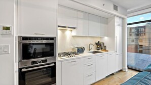A modern kitchen with integrated appliances, a built-in oven, and a window overlooking a cityscape. - Downtown |Views | Luxury | Sunny (Washington)