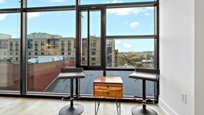 Enjoy a city view from the large window, featuring a minimalist design with a small table and two stools.