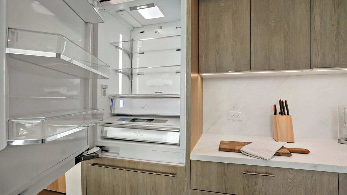 Un refrigerador abierto con repisas transparentes, un dispensador de hielo incorporado y una pantalla digital.