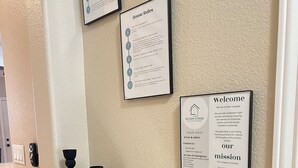 Zona de recepción de hotel con mostrador, cartel con las normas de la casa y señal de bienvenida.