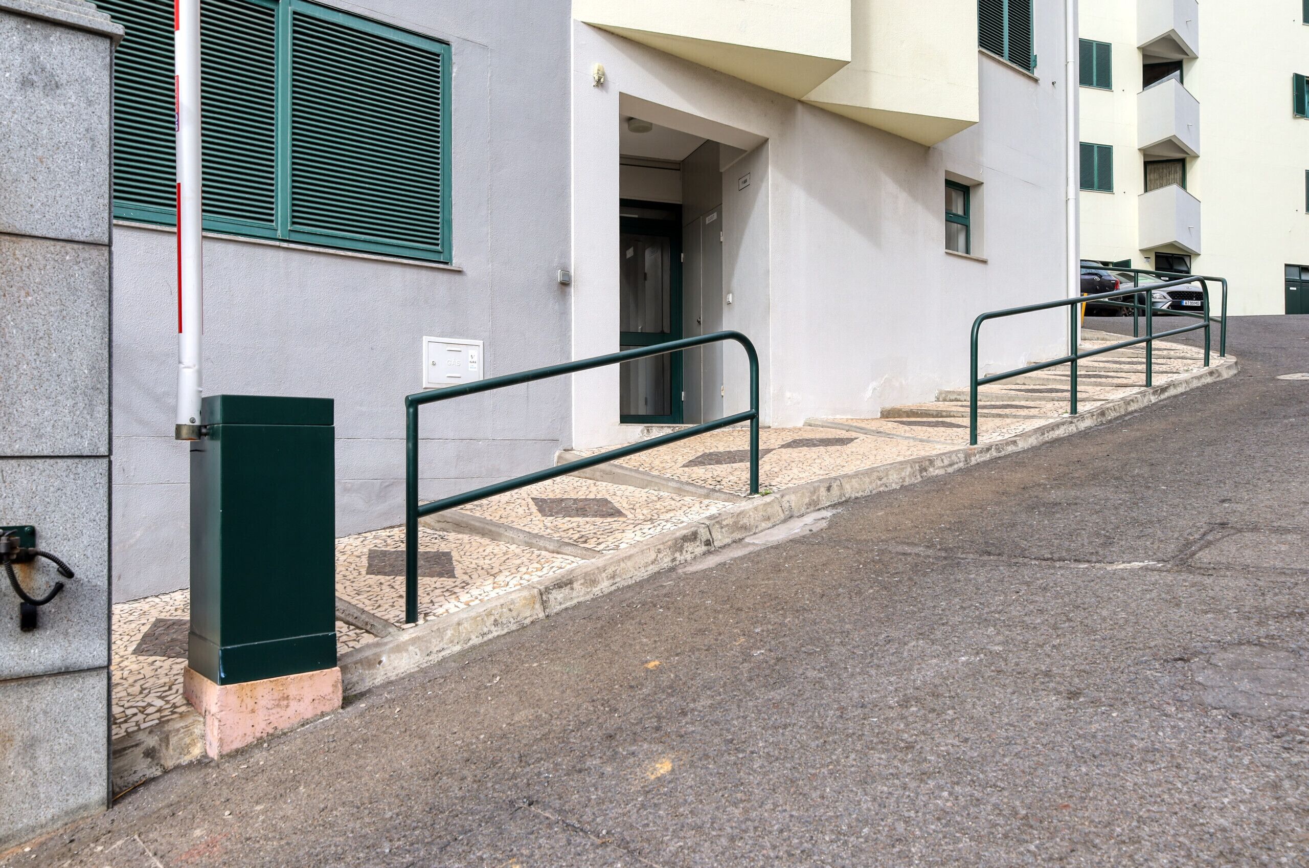 A building with a staircase leading to an entrance, a metal railing, and a door.