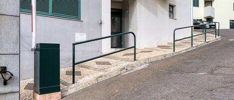 A building with a staircase leading to an entrance, a metal railing, and a door.