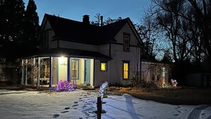 A house with a snow-covered driveway and footprints leading to the front door.