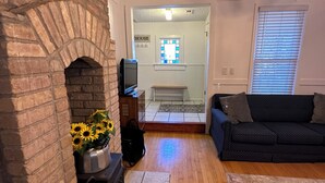 A living room with a brick fireplace, a sofa, and a television.