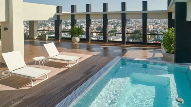 A rooftop pool area with lounge chairs and a view of the city. - GOISTAY ROMANTICA VISTA A LAS MONTAÑAS (Santo Domingo)