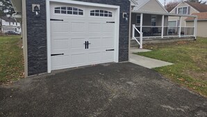 Un garage à l’extérieur en pierre et doté d’une porte de garage blanche.