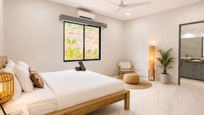A modern bedroom with a bed, bedside table, lamp, and a large window with a view. - Large Modern 3-BED house with pool, AC and WiFi in Uvita (Uvita)