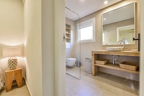 Une salle de bain moderne avec un grand miroir, un meuble-lavabo en bois et une douche à l’italienne.
