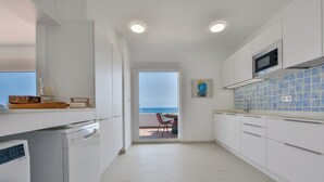 A modern kitchen with white cabinetry, a microwave, and a view to the outside. - Moraira Bay 6 - By Almarina Villas (MORAIRA)