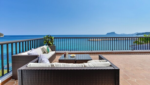 A balcony with wicker furniture, a glass table, and a view of the sea. - Moraira Bay 6 - By Almarina Villas (MORAIRA)