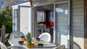 An outdoor dining area with a table set for breakfast, including a pineapple and orange juice. - Le Tadorne by Interhome (Carnac)