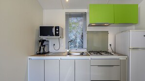 A compact kitchen with a microwave, coffee maker, sink, stove, and a refrigerator. - Le Courlis by Interhome (Carnac)