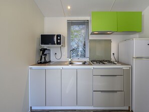 Een koelkast, een microgolfoven, kookgerei, borden en bestek