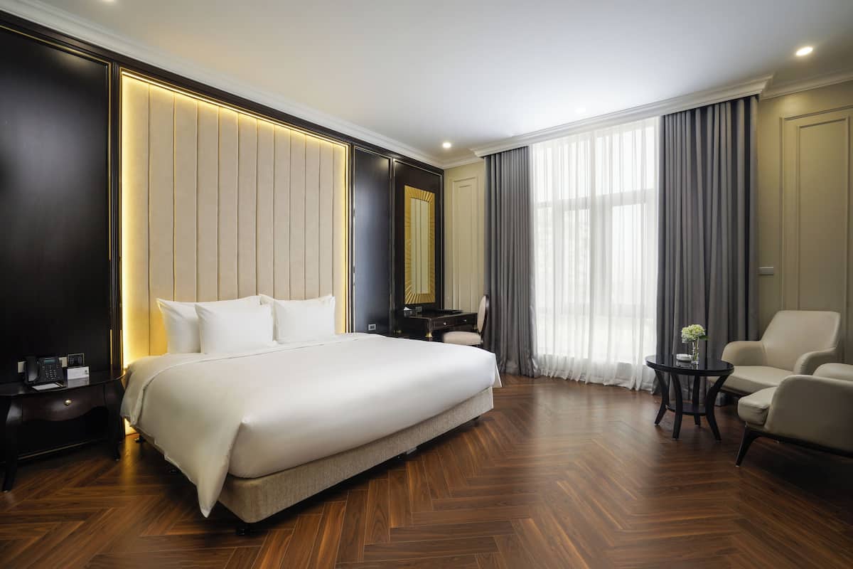 A hotel room with a large bed, a desk, a chair, and a view of the outdoors.
