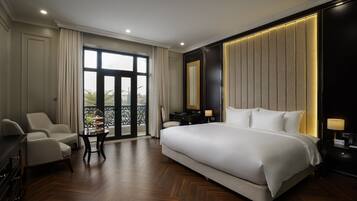 A spacious bedroom with a large bed, a seating area with chairs, a small table, and a balcony view.
