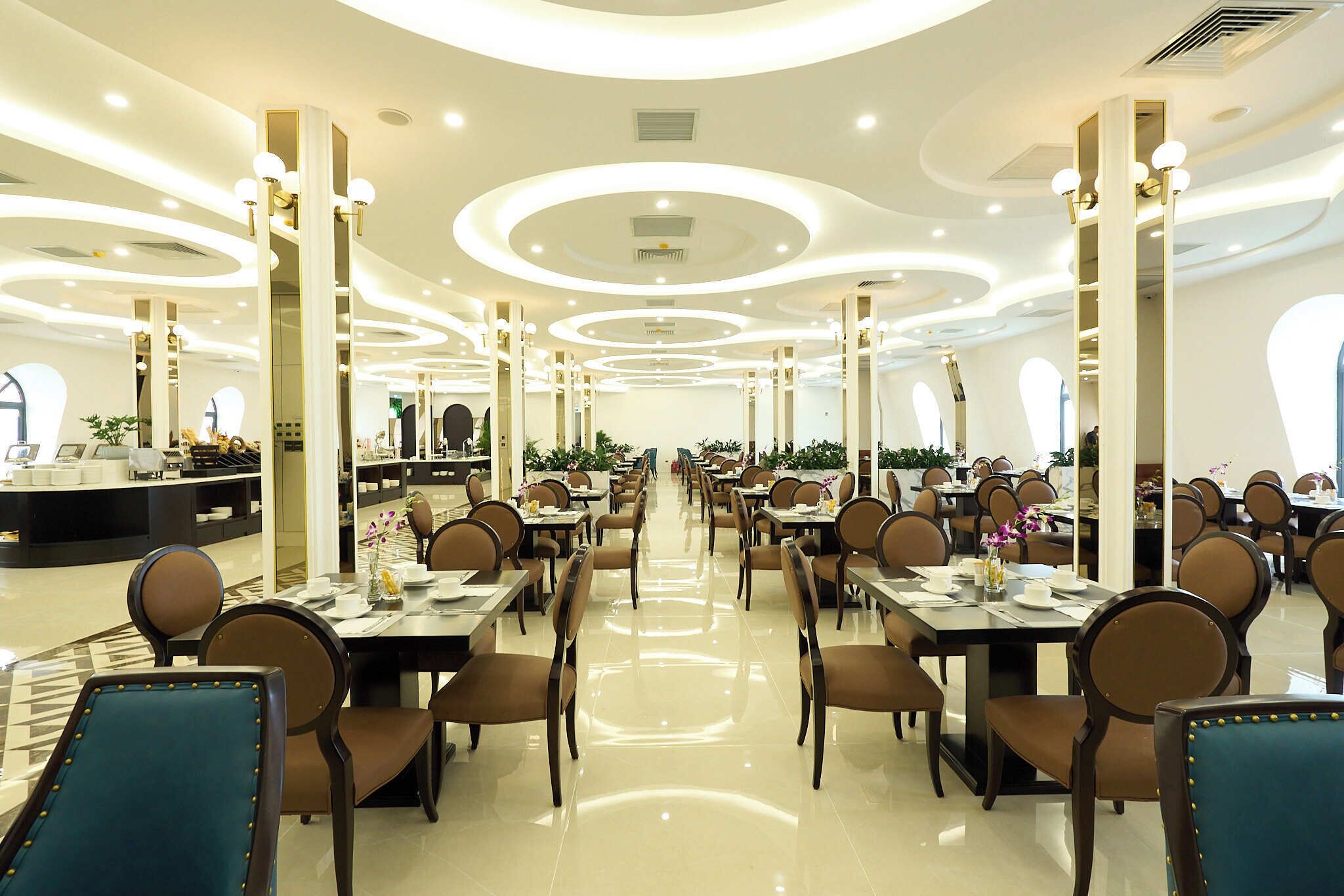 A spacious dining area with multiple tables and chairs, a central counter, and decorative lighting.