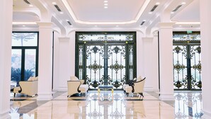 A spacious lobby with high ceilings, large windows, and ornate black metal gates. - Adamo Hotel Hung Yen (Yen My)