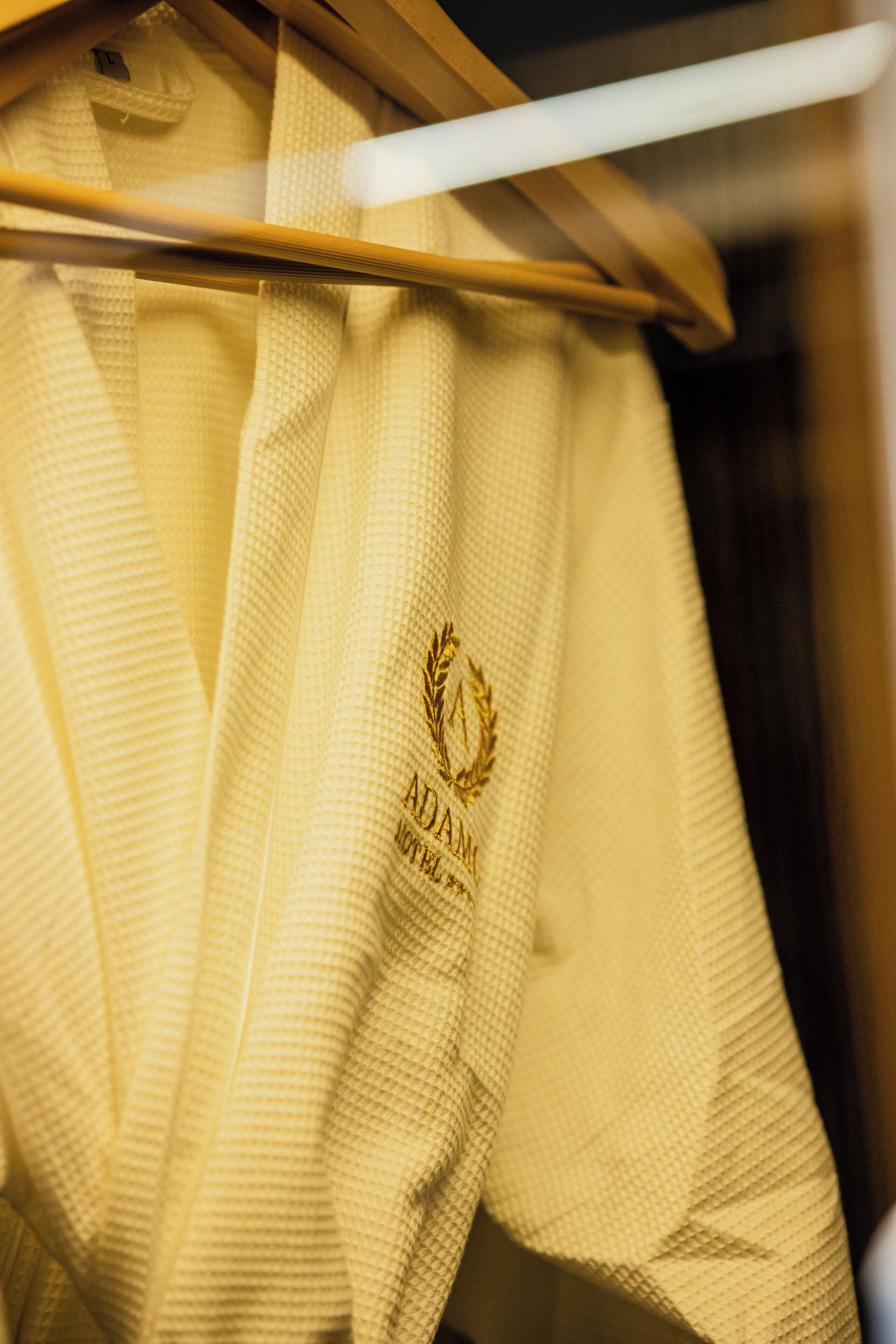 A yellow towel with a logo and text on a wooden hanger.