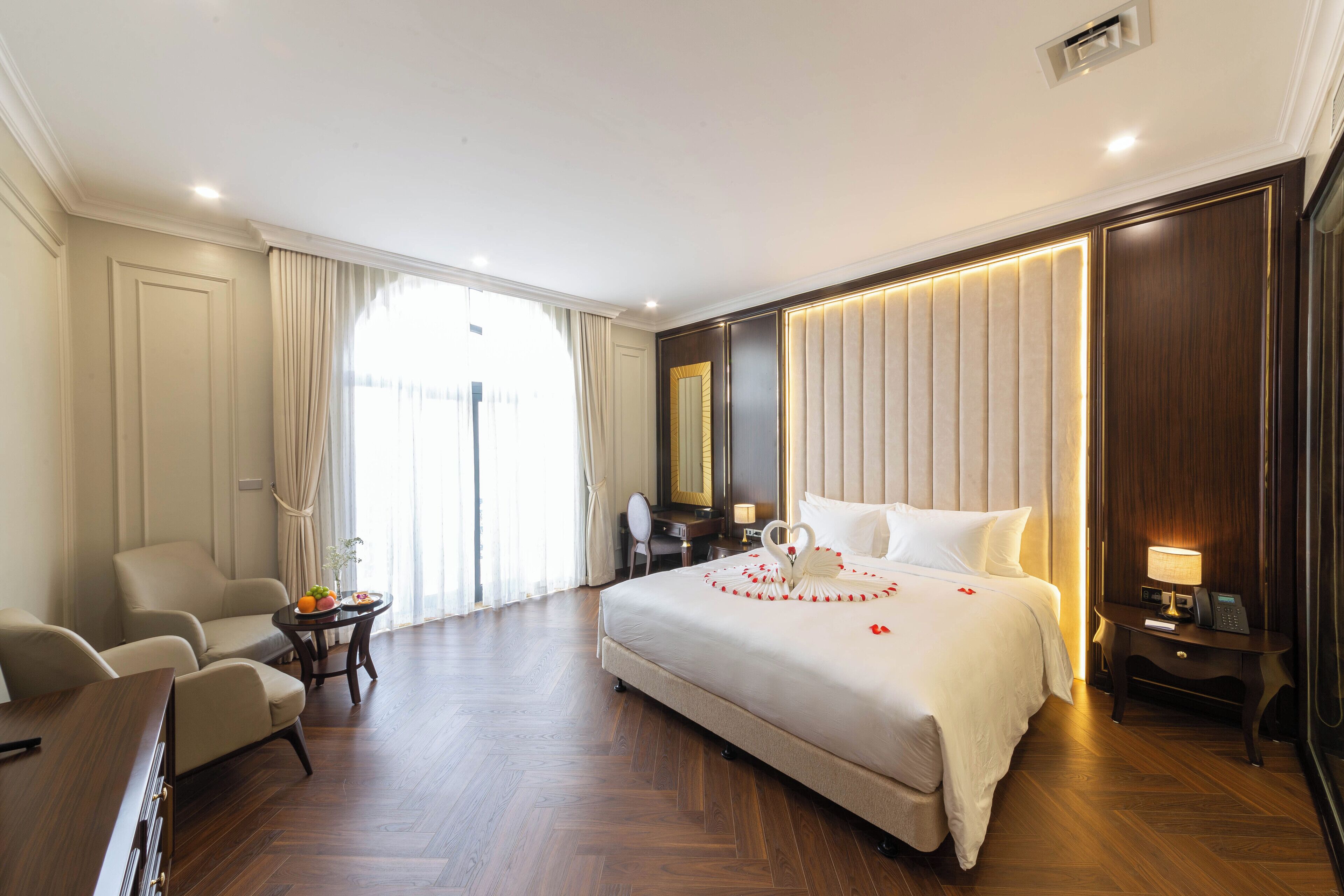 Habitación de hotel con una cama grande, un escritorio, una silla y una mesita con fruteros.