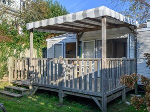 Una casa móvil con una terraza de madera y un porche cubierto.