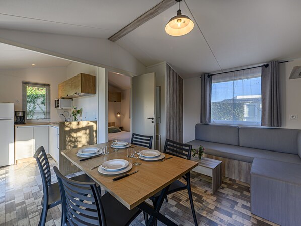 Un espacio habitable moderno y funcional con comedor, kitchenette y zona de estar junto a una ventana.