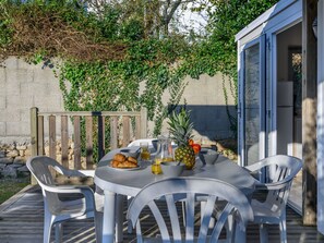 Un espacio de comedor al aire libre con una mesa para dos, rodeado de sillas de plástico blancas.
