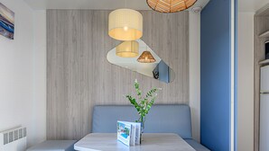 Ein modernes Wohnzimmer mit einem grauen Sofa, einem kleinen Tisch mit einer Zeitschrift und einer Pendelleuchte.