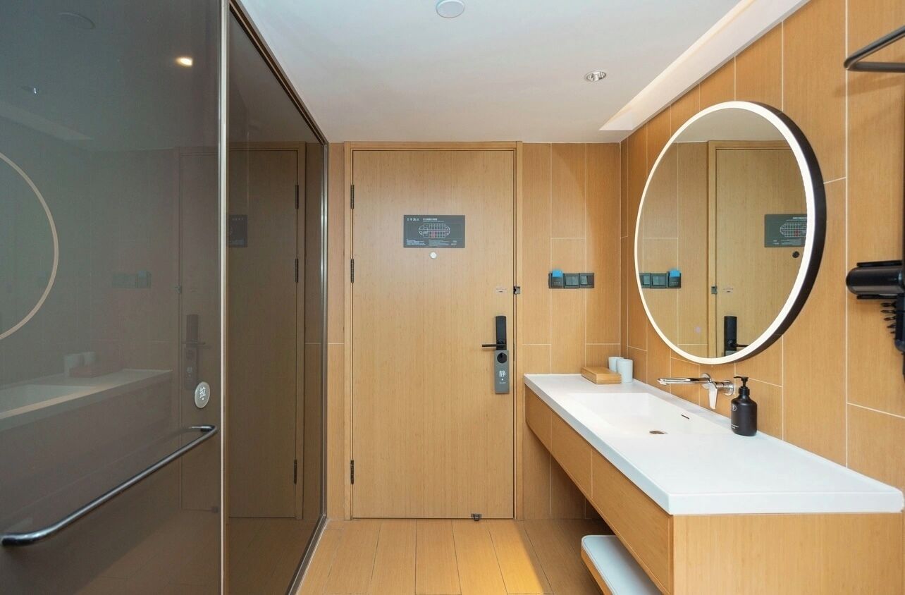 A modern bathroom with a wooden vanity, a large mirror, and a glass shower enclosure.