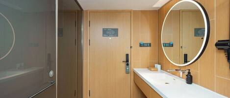 A modern bathroom with a wooden vanity, a large mirror, and a glass shower enclosure.