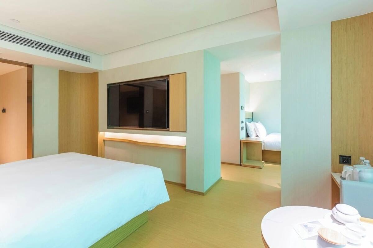 Ein Hotelzimmer mit Bett, Fernseher, Schreibtisch, Badezimmer und einem kleinen Tisch mit Toilettenartikeln.