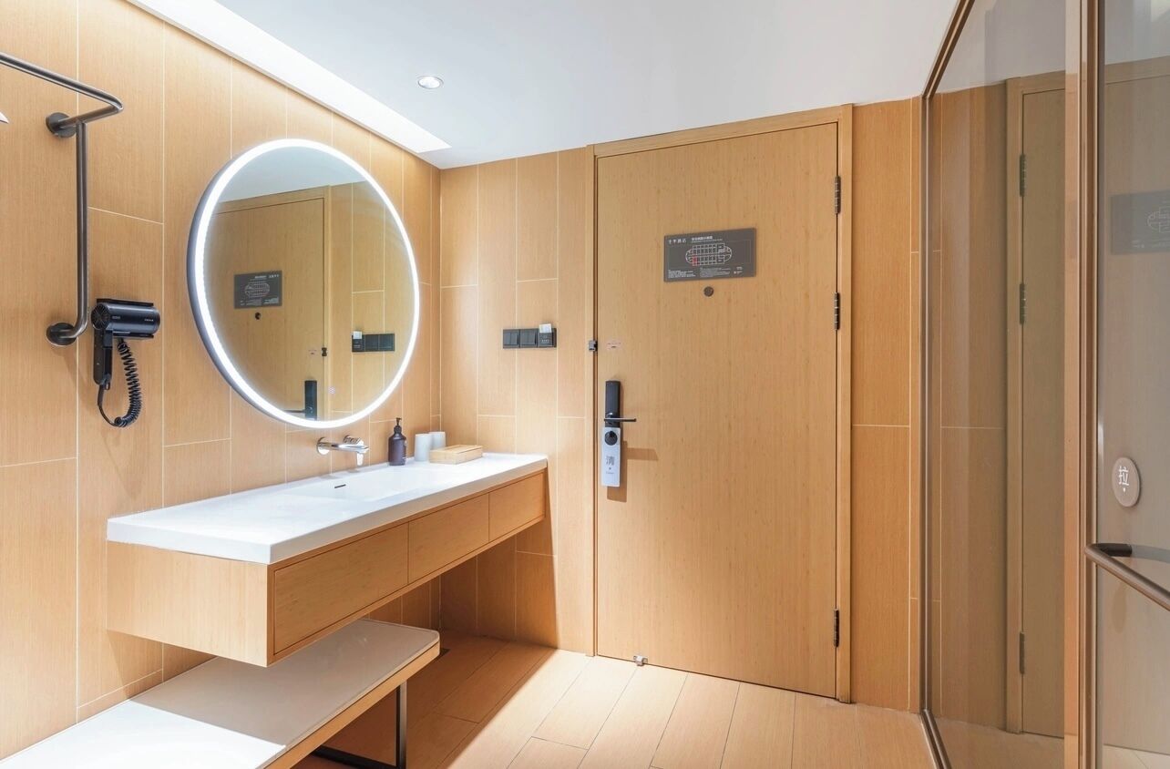 A modern bathroom with a white sink, a round mirror, and a handheld showerhead.