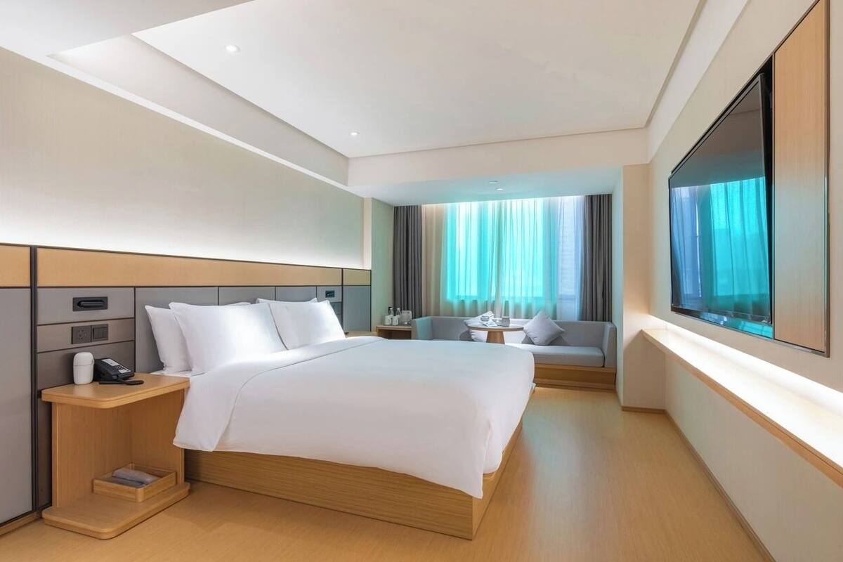 Ein modernes Hotelzimmer mit einem großen Bett, Nachttischen, einer Couch und einem Fernseher.