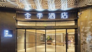 La entrada a un hotel de diseño moderno, con fachada de vidrio y un letrero con caracteres chinos.
