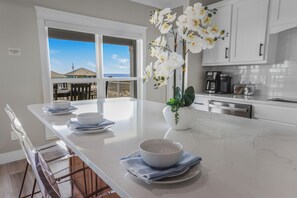 A kitchen with a large island, white cabinets, and a view of the ocean.