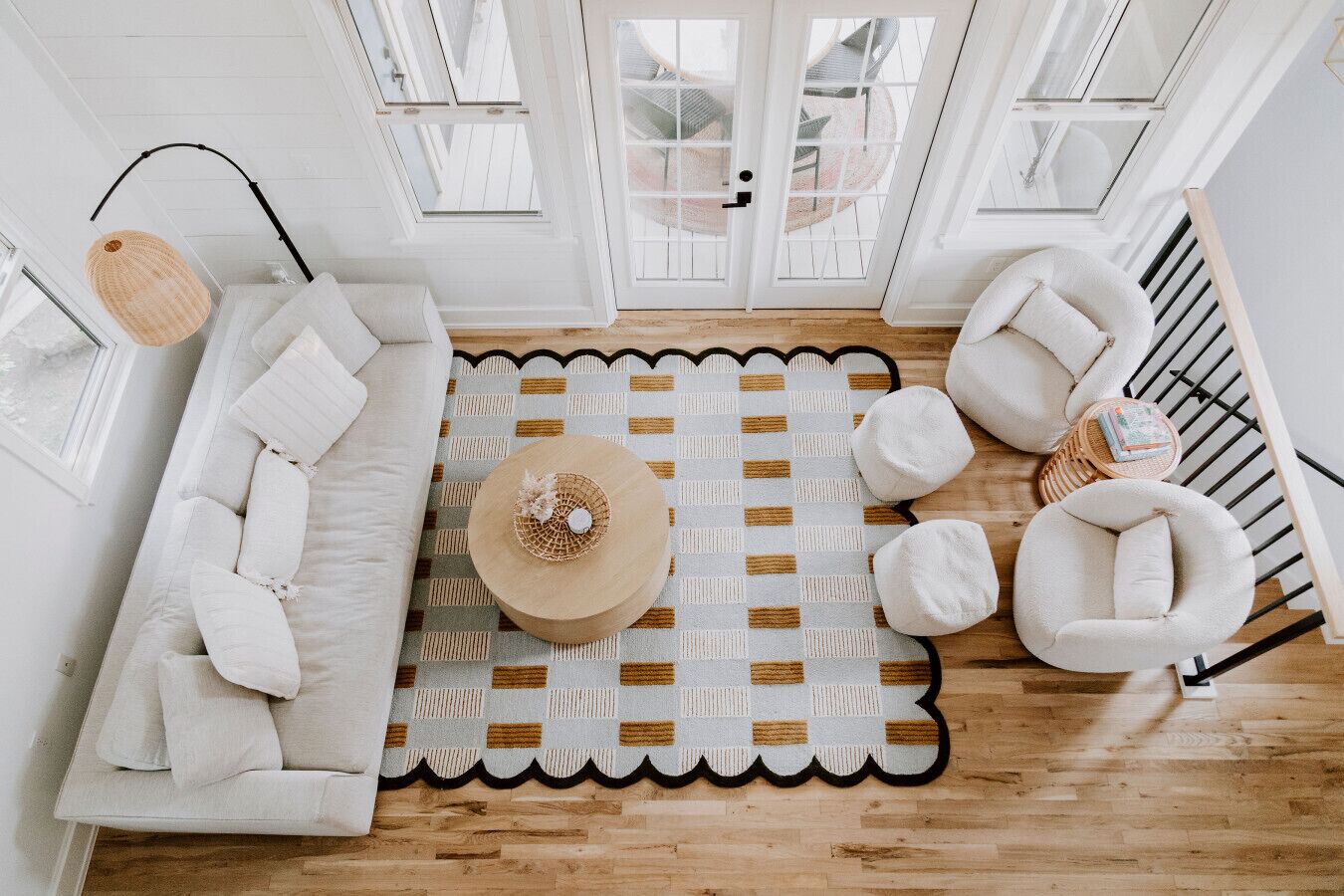 A modern living room with a white sofa, a round coffee table, and a patterned rug.