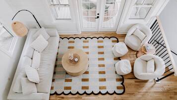 A modern living room with a white sofa, a round coffee table, and a patterned rug.