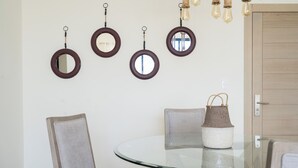Un coin repas avec une table en verre, deux chaises et un luminaire suspendu.