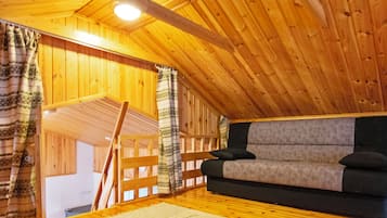 Tunnelmallinen ullakkohuone, jossa on puuseinät ja kalteva katto.