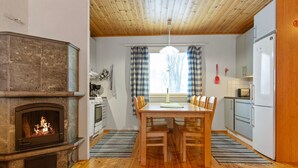 Et hyggeligt køkken med pejs, træspisebord og moderne hårde hvidevarer.