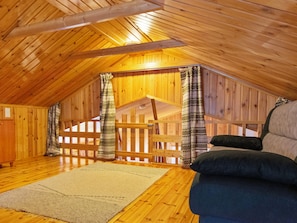 Een houten interieur met een schuine kap, een houten trap en een bank.